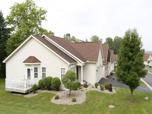 a row of white houses with a yard and trees