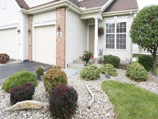 a front yard with rocks and plants in front of a house