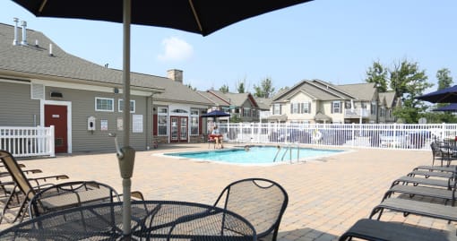 a swimming pool with chairs and umbrellas in front of houses