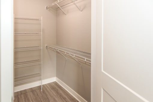 a walk in closet with empty shelves and a door