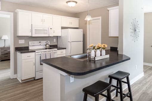 a kitchen with white appliances and a counter with stools