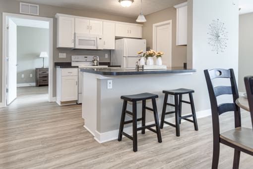 an open kitchen and dining area with a counter and stools