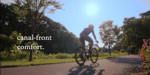 A person riding a bicycle on the Erie Canal path near Westport Crossing in Pittsford, NY