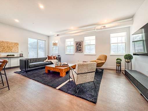 A living room with a black couch, a wooden coffee table, and a yellow chair.