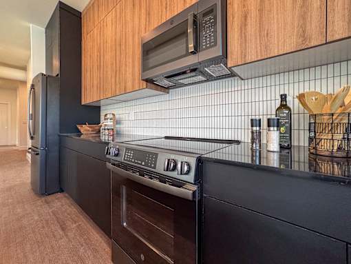 A modern kitchen with dark wood cabinets and black appliances.