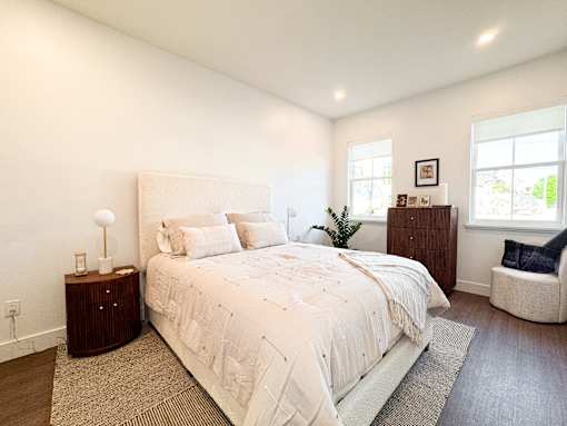 A bedroom with a large bed, a nightstand, and a chair.