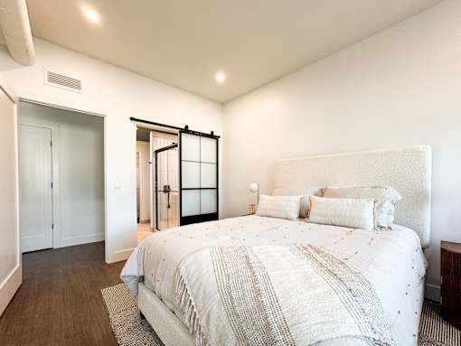 A bedroom with a large bed and a sliding glass door.