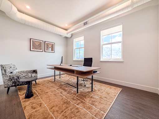 A room with a desk, chair, and rug.