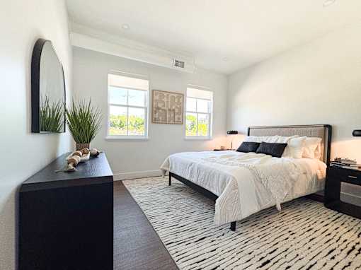 A bedroom with a large bed and a black and white patterned rug.