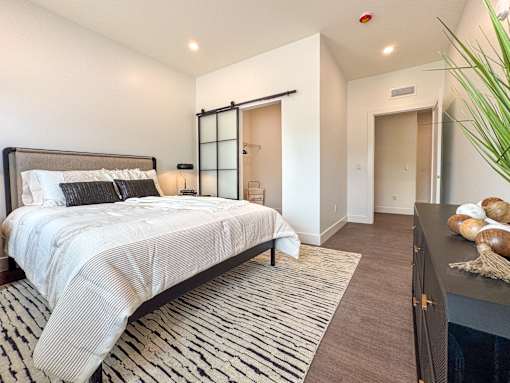 A bedroom with a large bed and a black and white striped rug.