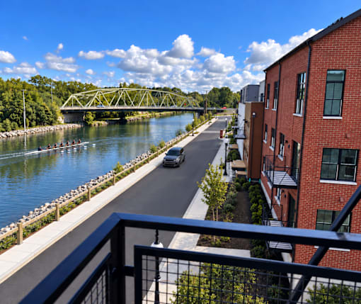 A car is driving down a street next to a river.