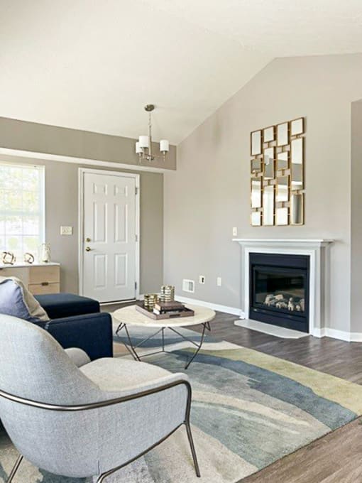View of living area in ranch townhome great room with fireplace, cathedral ceiling, and faux hardwood floors