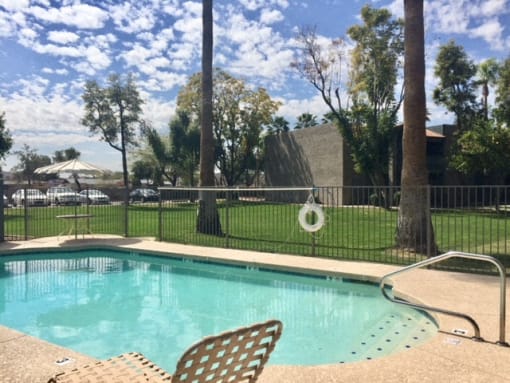 a swimming pool with chairs next to a fence