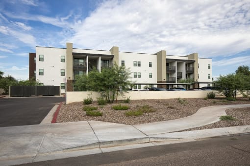 an exterior view of an apartment building with a parking lot