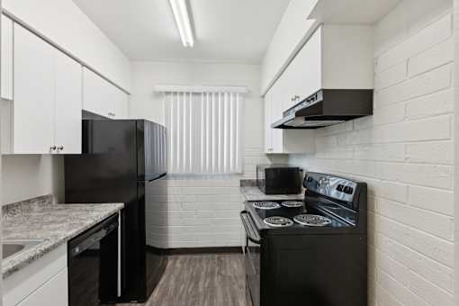 A kitchen with black appliances and white cabinets.