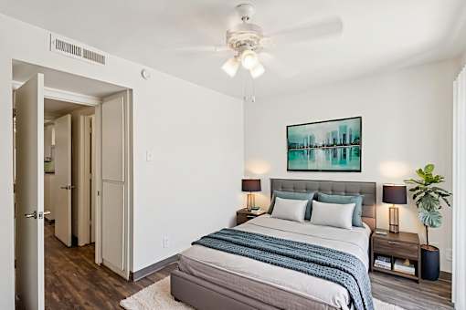 A bedroom with a bed, nightstands, and a painting on the wall.