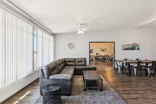 A living room with a couch, a table, and a ceiling fan.