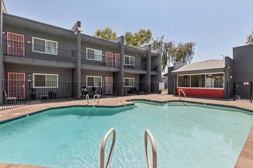 A swimming pool in front of a building with a red and black exterior.