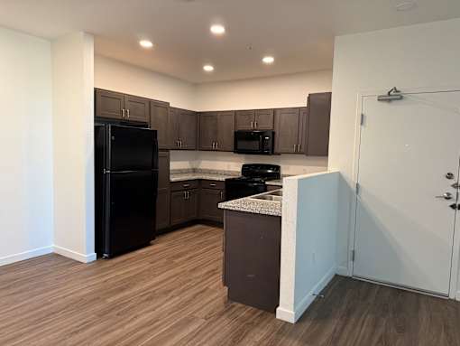 A kitchen with a black fridge, microwave and oven.