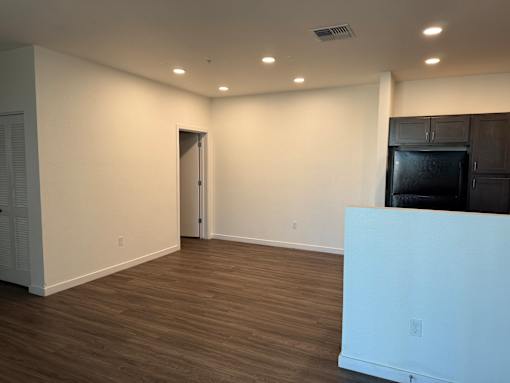A room with a white wall and brown flooring.
