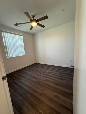 A room with a ceiling fan and wooden flooring.