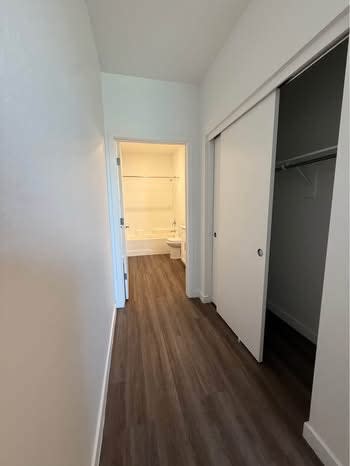 A long hallway with white walls and wood flooring.