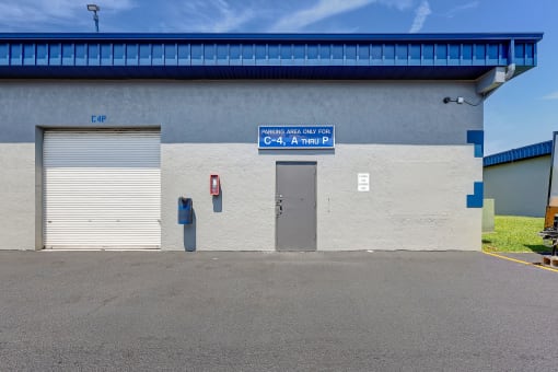 the front of a building with two garage doors and a blue sign on the side