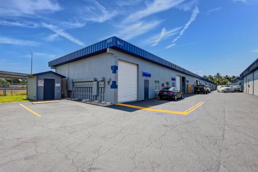 a white building with a blue roof and a parking lot with cars