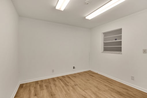 a room with white walls and wooden floors and a window