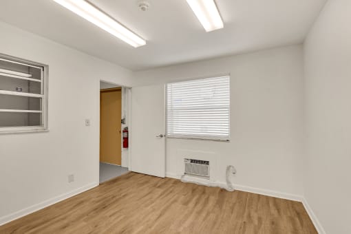 a living room with white walls and wood flooring and a window