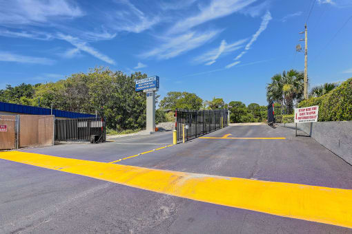 the entrance to a parking lot with a gate and a street sign on the side