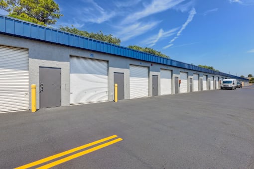 the side of a warehouse building with roller shutter doors and a truck parked outside