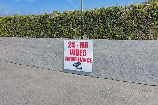 a video surveillance sign on a wall next to a sidewalk