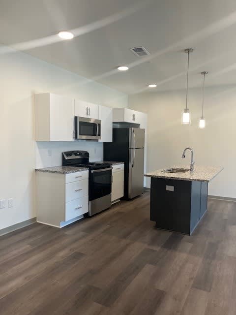 A kitchen with a black fridge and white cabinets.