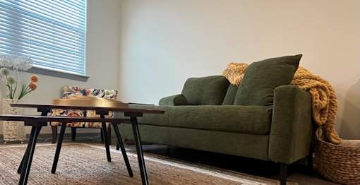 A green couch with a brown table in front of it.