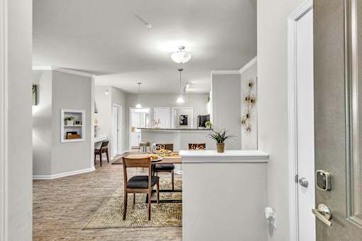 A dining room with a table set for two and a kitchen in the background.