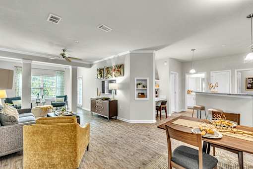 A well-lit living room with a dining area and kitchen in the background.