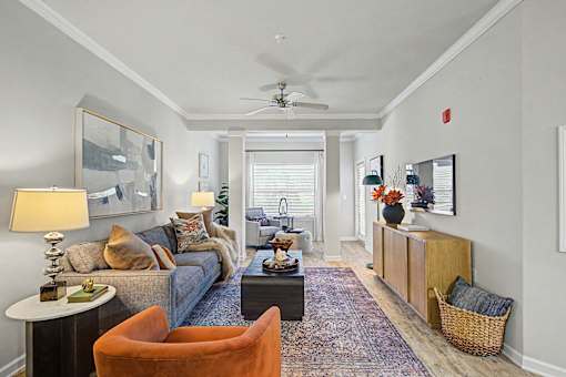 A living room with a grey couch, a brown chair, a white side table and a rug.