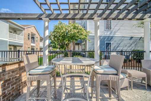 A patio with a table and chairs under a pergola.