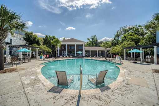 A large swimming pool surrounded by lounge chairs and umbrellas.