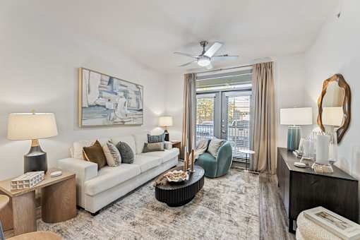 A living room with a white couch, a painting on the wall, and a ceiling fan.