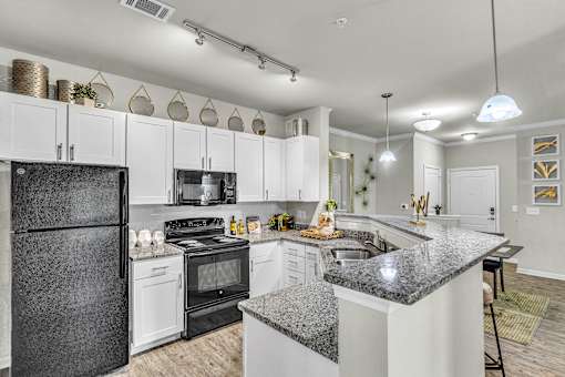 A modern kitchen with a black refrigerator and white cabinets.