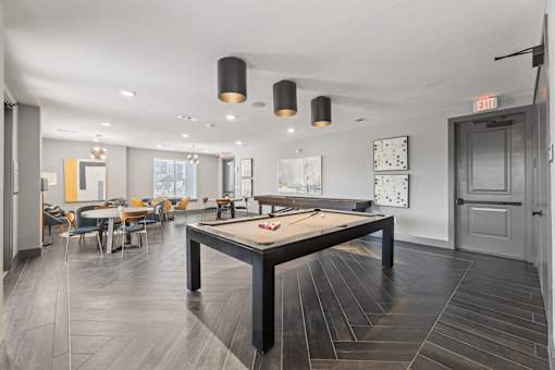 A pool table is in the middle of a room with a wooden floor.