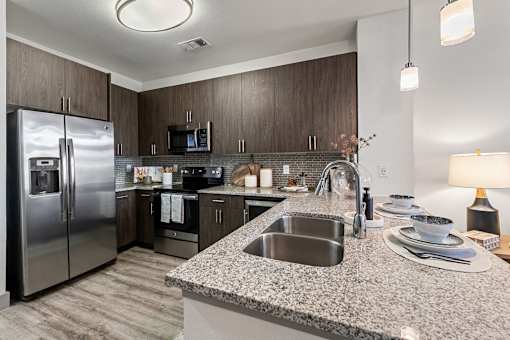 A modern kitchen with a granite countertop and stainless steel appliances.