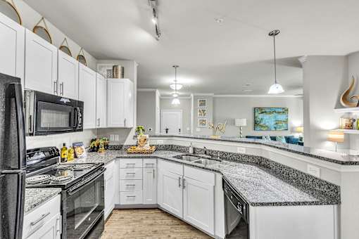 A kitchen with white cabinets and black appliances.