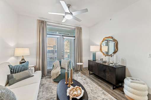 A living room with a white sofa, a wooden sideboard, a mirror, and a ceiling fan.