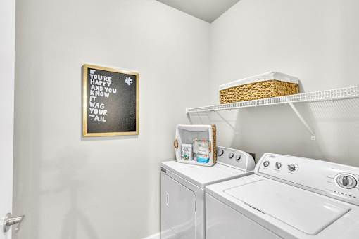 A laundry room with a washer and dryer and a framed sign on the wall.