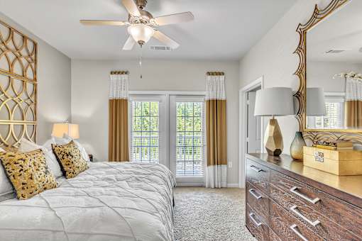 A bedroom with a large bed, a dresser, and a ceiling fan.