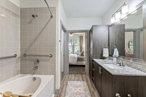 A bathroom with a white tub and a wooden vanity.