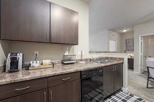 A kitchen with dark brown cabinets and granite countertops.